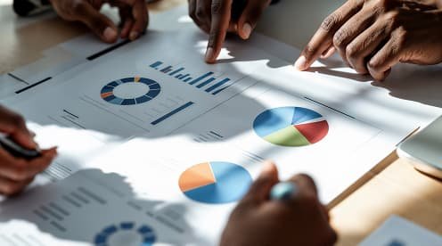 Business professionals collaborate on a document featuring graphs and charts, discussing data insights together.
